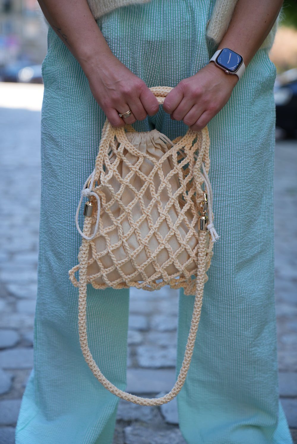 Kobieta trzymająca w ręku torebkę sznurkową Wiki w odcieniu masełkowym Sirka handmade