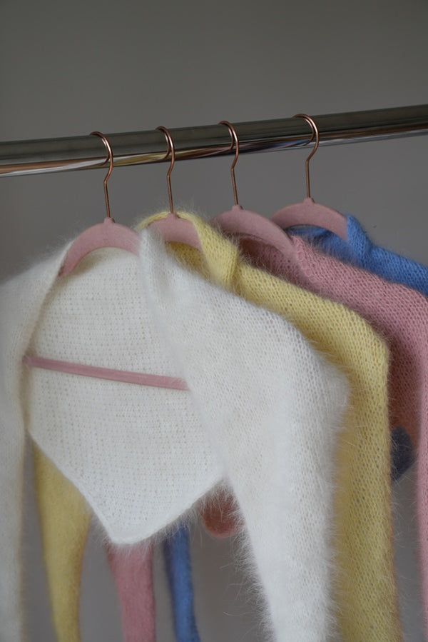 Chusty z angory i wełny merino Sirka handmade wiszące na wieszakach w odcieniach od lewej biały, masełkowy, różowy, niebieski
