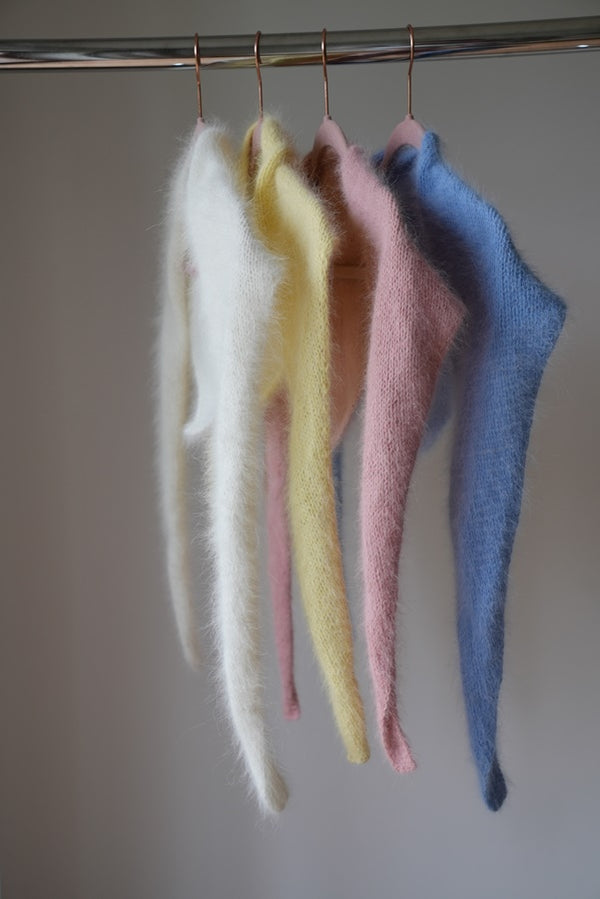 Chusty z angory i wełny merino Sirka handmade wiszące na wieszakach w odcieniach od lewej biały, masełkowy, różowy, niebieski