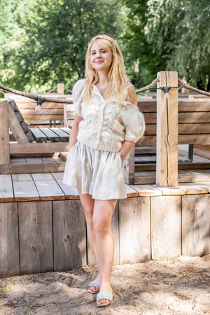 Uśmiechnięta kobieta na plaży w kardiganie Inga z alpaki suri & merino Sirka handmade