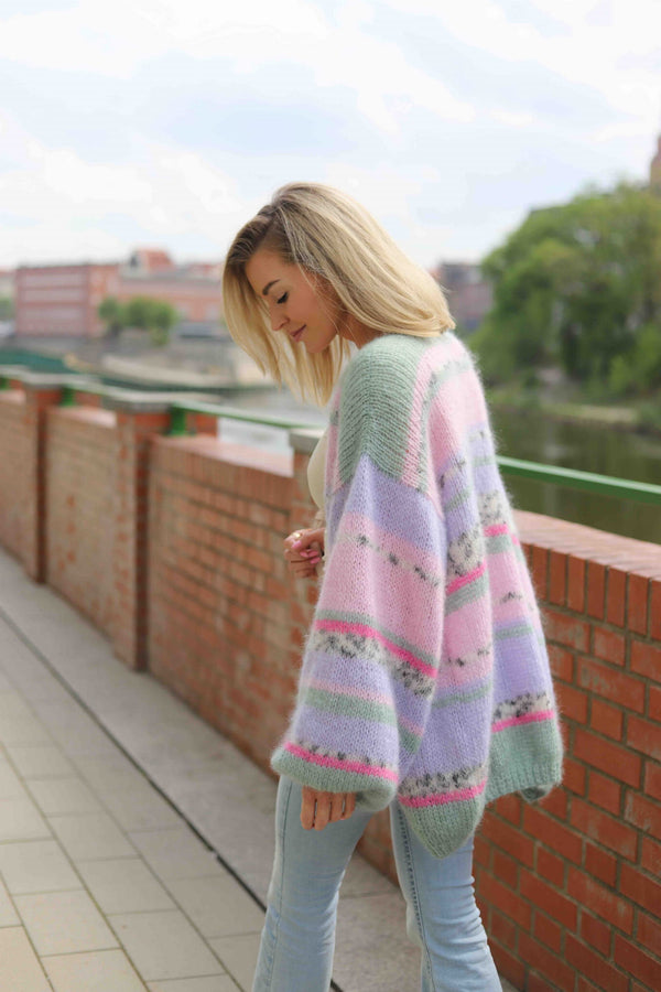 Kobieta idąca przez uliczkę w wełnianym, kolorowym kardiganie Izabella Sirka handmade 