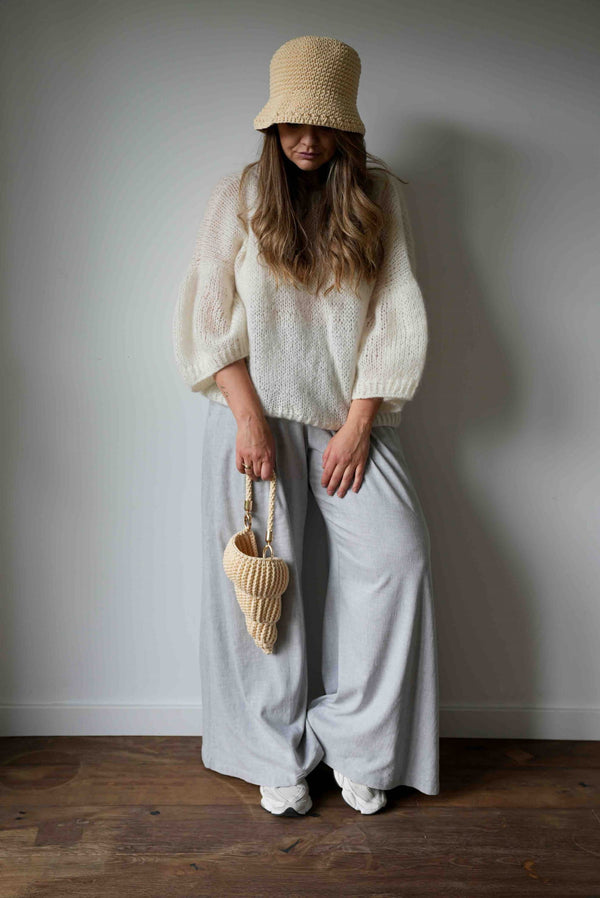Stojąca kobieta w swetrze, torebką muszelka i w bawełnianym kapeluszu w odcieniu masełkowym Sirka handmade