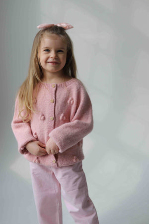 Uśmiechnięta dziewczynka w różowym dziecięcym kardiganie Sirka handmade