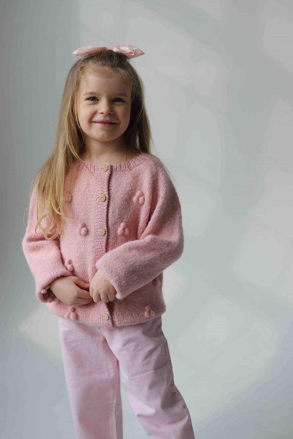 Uśmiechnięta dziewczynka w różowym dziecięcym kardiganie Sirka handmade
