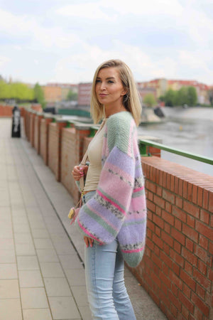 Kobieta idąca przez uliczkę w wełnianym, kolorowym kardiganie Izabella Sirka handmade 