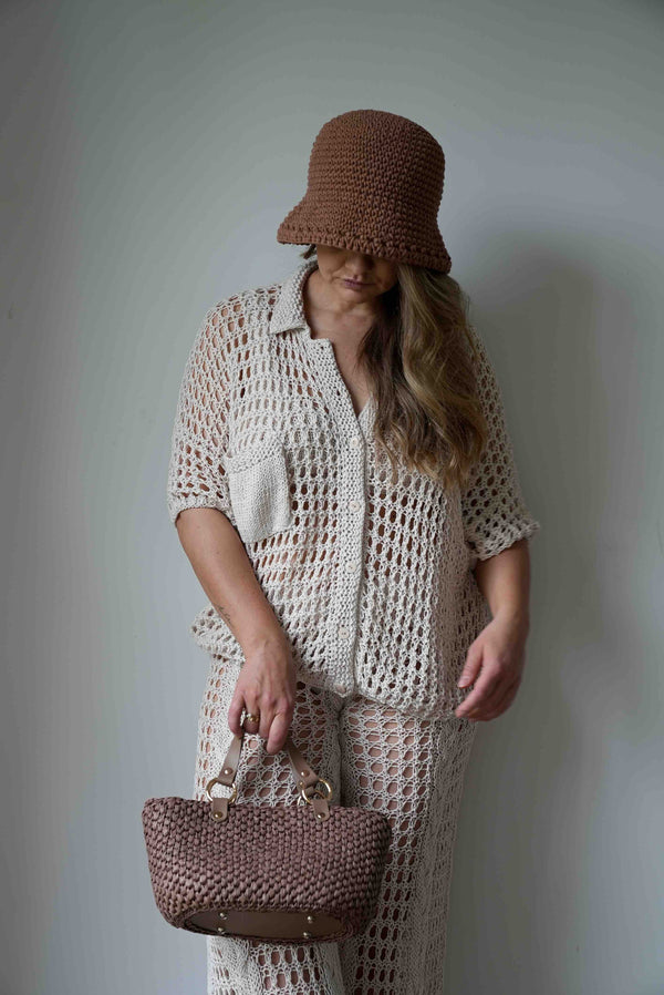 Kobieta patrząca w dół w kapeluszu z torebką w bluzce z kołnierzykiem Sirka handmade