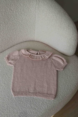 Jedwabny dziecięcy t-shirt Sirka handmade w odcieniu pudrowy róż leżacy na fotelu