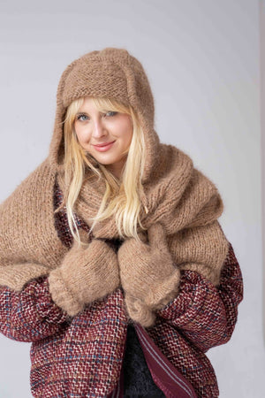 Uśmiechnięta kobieta w uszance, szalu i rękawiczkach Sirka handmade w odcieniu beżowym