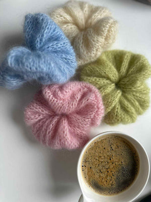 Cztery gumki do włosów scrunchie robione ręcznie w kolorach różowy, limonkowy, błękitny, ecru na stoliku z kawą