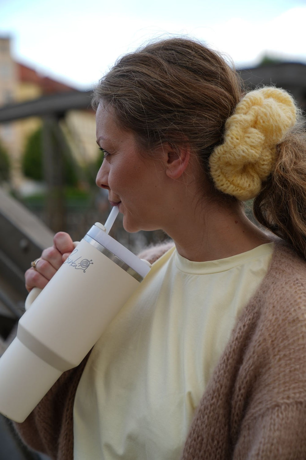 Kobieta pijąca z kubka z włosami spiętymi w kucyk gumką scrunchie Sirka handmade