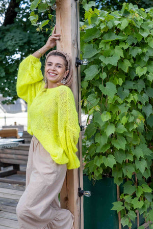 Uśmiechnięta kobieta w neonowym swetrze Lia z suri alpaki Sirka
