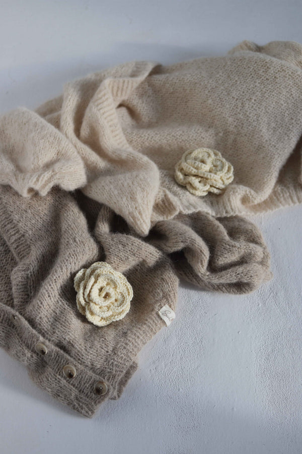 Dwa leżące swetry z broszkami kwiatkami Sirka handmade