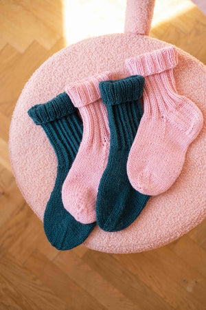 Leżące na pufie wełniane skarpetki Merry od Sirka handmade
