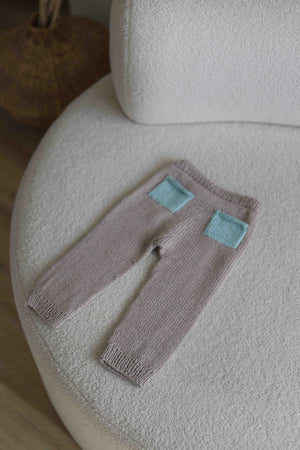 Dziecięce spodenki ręcznie dziergane leżące na kanapie Sirka handmade