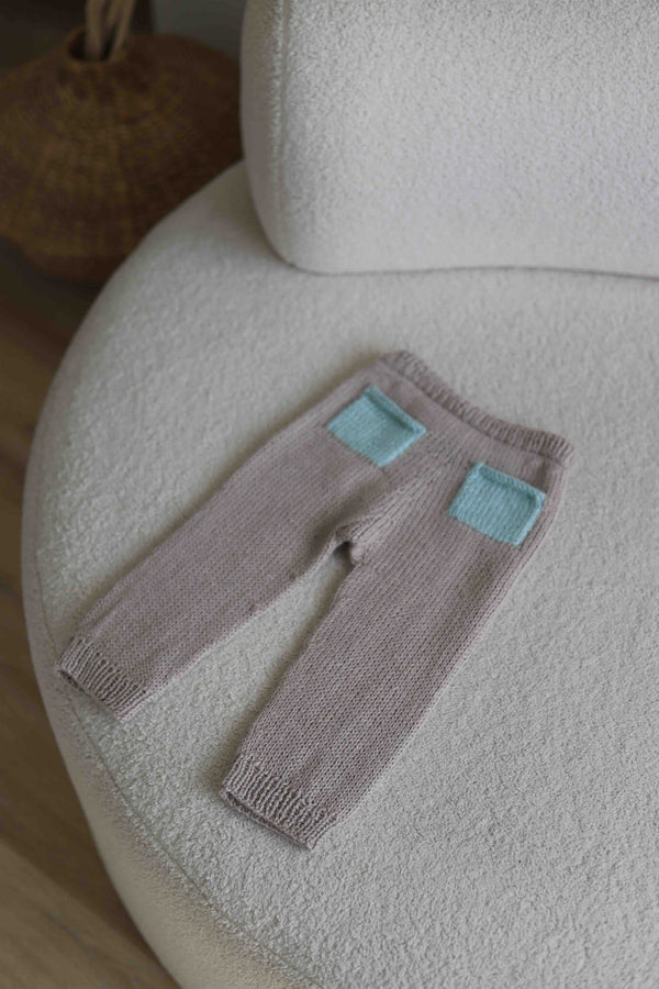 Dziecięce spodenki ręcznie dziergane leżące na kanapie Sirka handmade