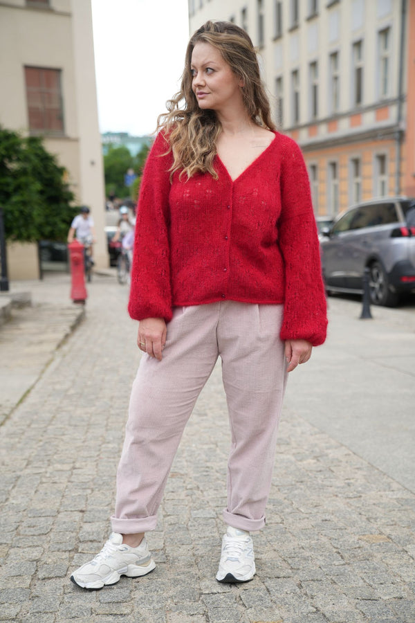 Kobieta patrząca w bok w czerwonym kardiganie SIrka handmade na tle miasta