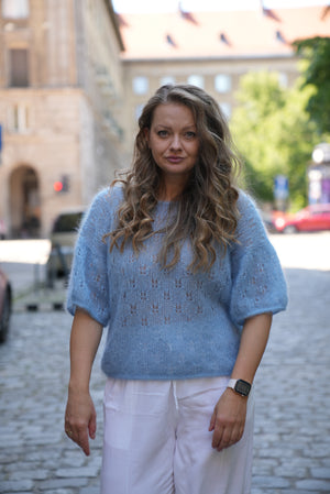 Kobieta w błękitnej bluzeczce Ewa Sirka handmade na tle miasta