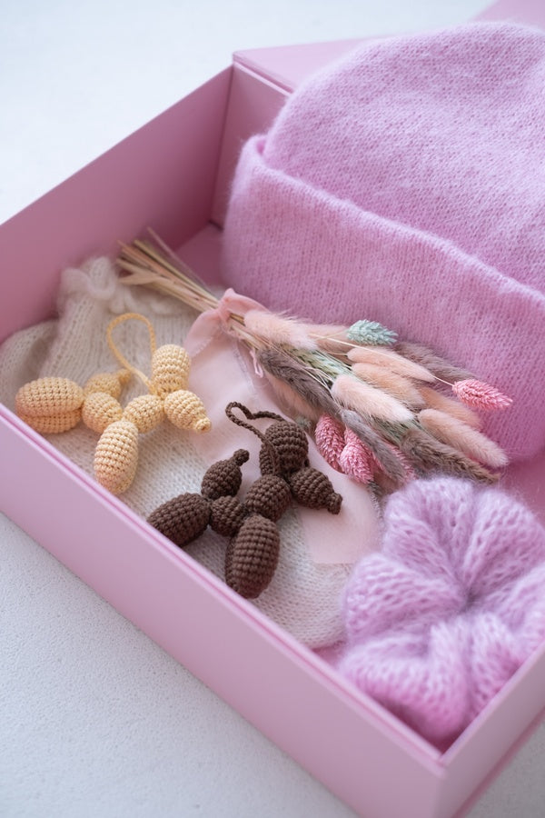 Pudełko z suszkiem kwiatów, czapką, breloczkami i gumką do włosów