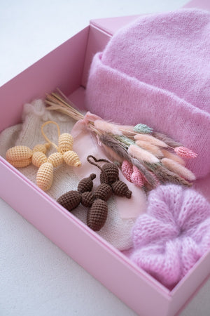 Pudełko z suszkiem kwiatów, czapką, breloczkami i gumką do włosów