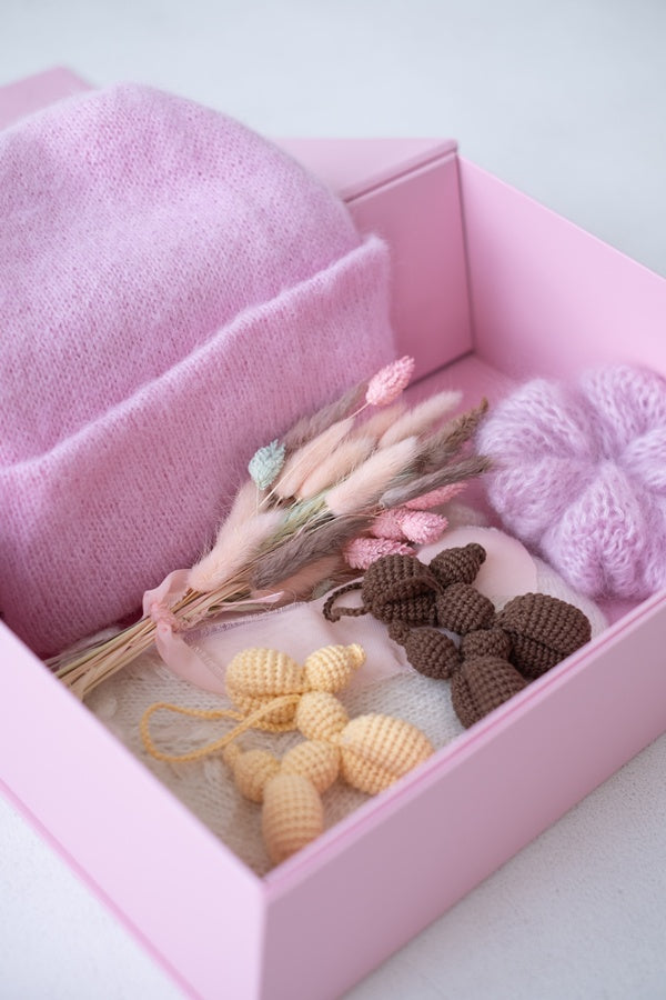 Pudełko z suszkiem kwiatów, czapką, breloczkami i gumką do włosów