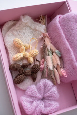 Pudełko z suszkiem kwiatów, czapką, breloczkami i gumką do włosów