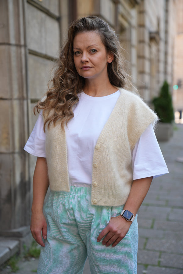 Kobieta w kamizelce w odcieniu masełkowym Sirka handmade na tle miasta